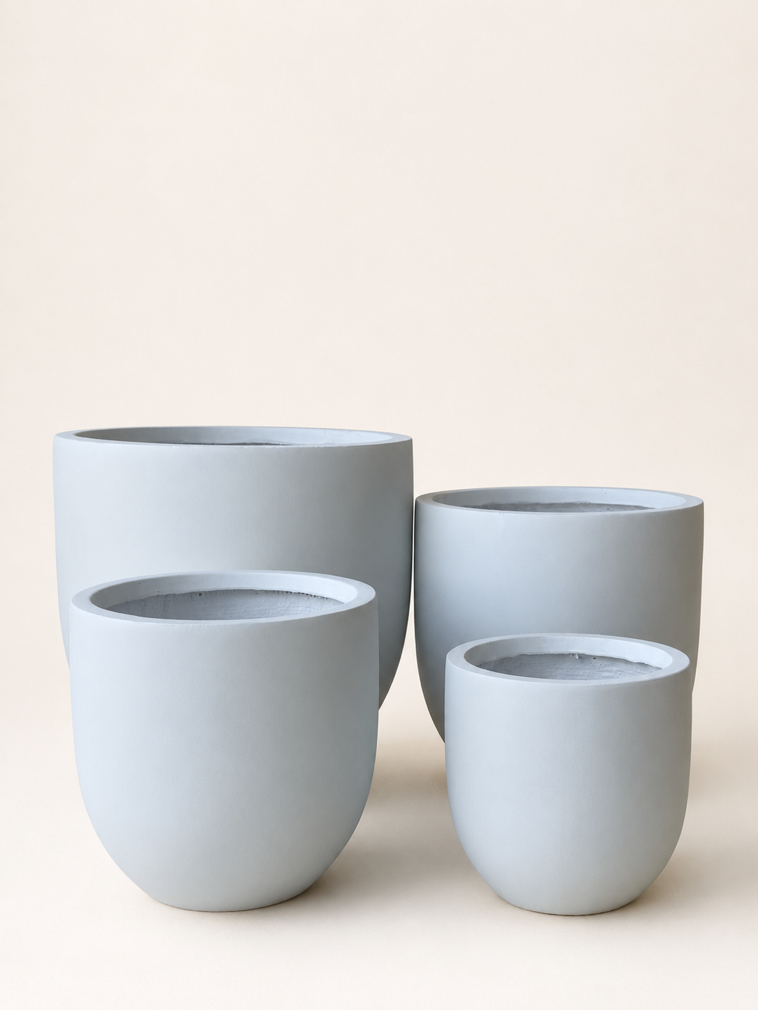 Set of four matte fiber clay planters, rounded rims, light blue-gray finish