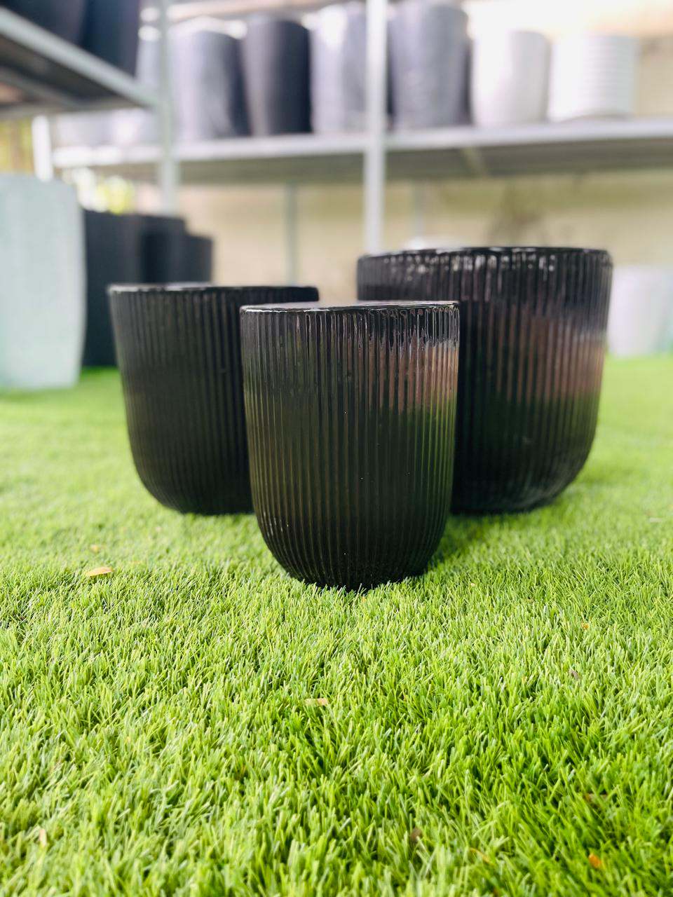 Black ceramic low planter pot with vertical ribbed texture, short round shape