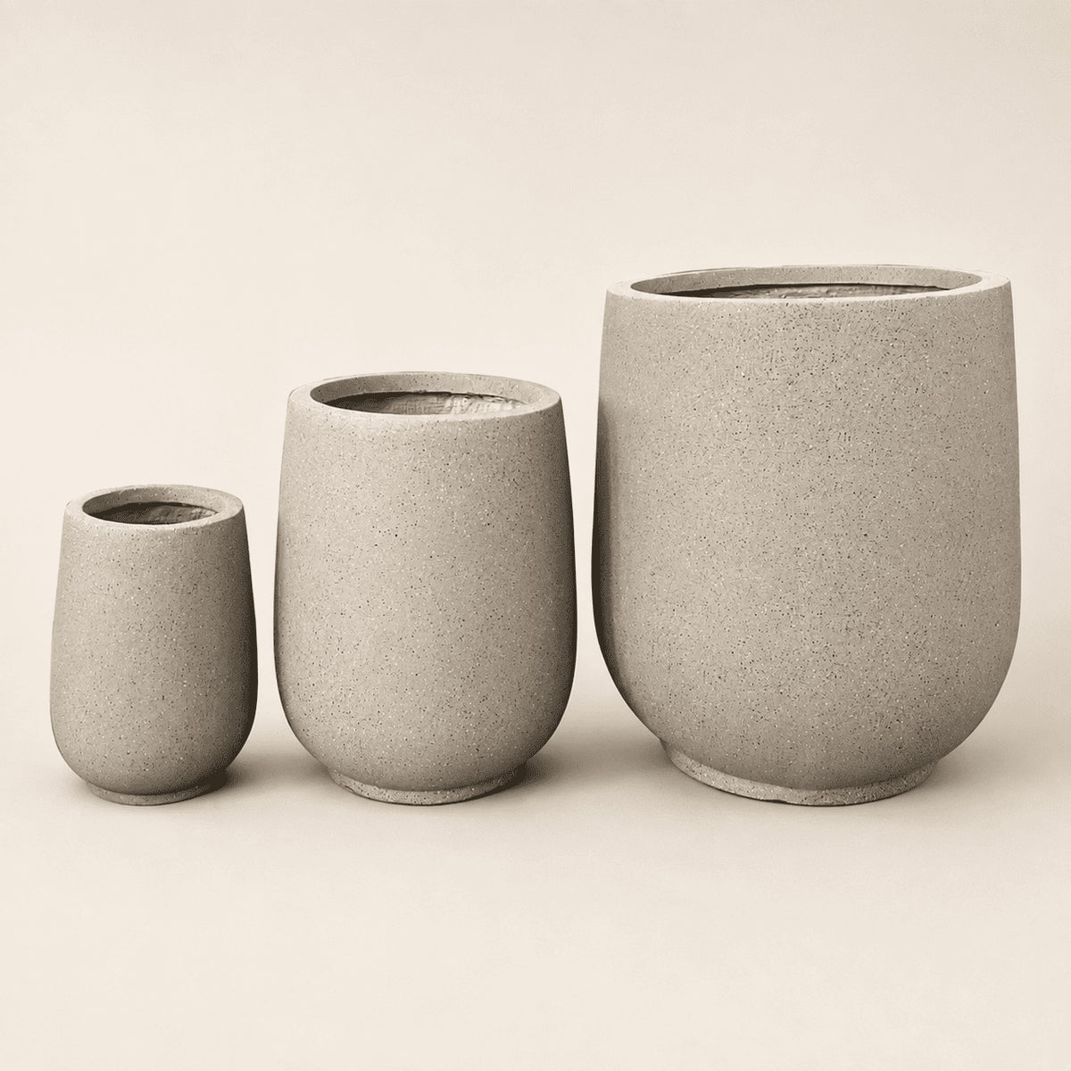 Sand-colored round concrete planters set of three, varying heights, open top