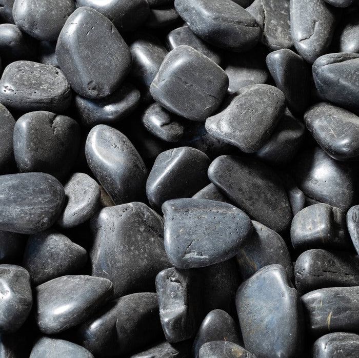 Dark gray black pebbles, smooth rounded stones with natural speckled texture.
