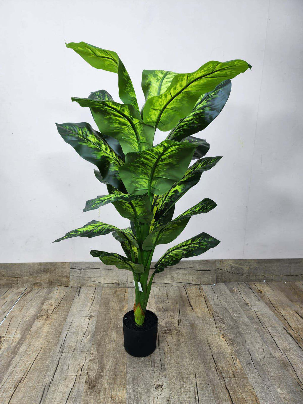 Artificial dieffenbachia plant with green variegated leaves in black pot