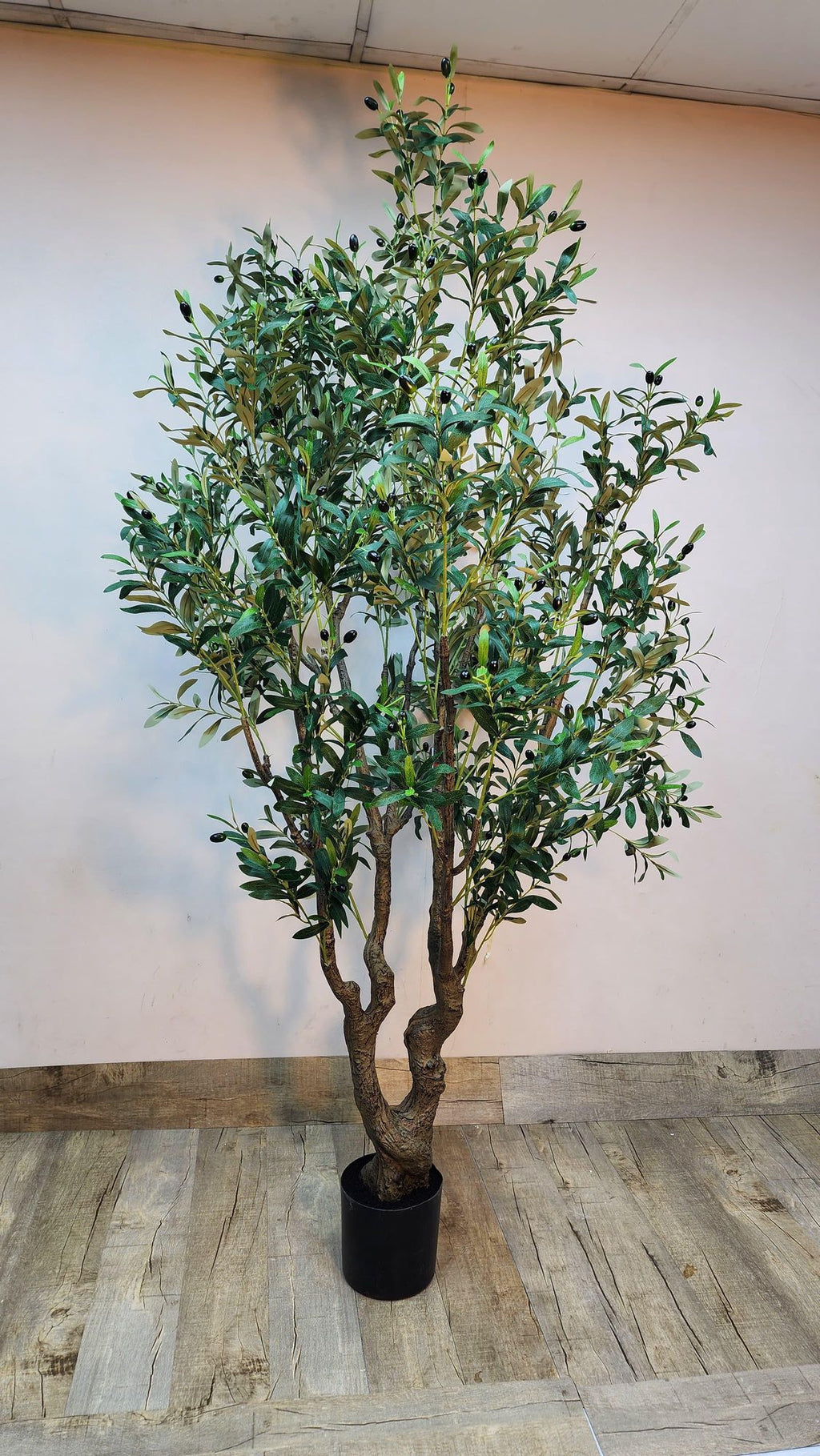 Large artificial olive tree with dense green leaves in a black pot