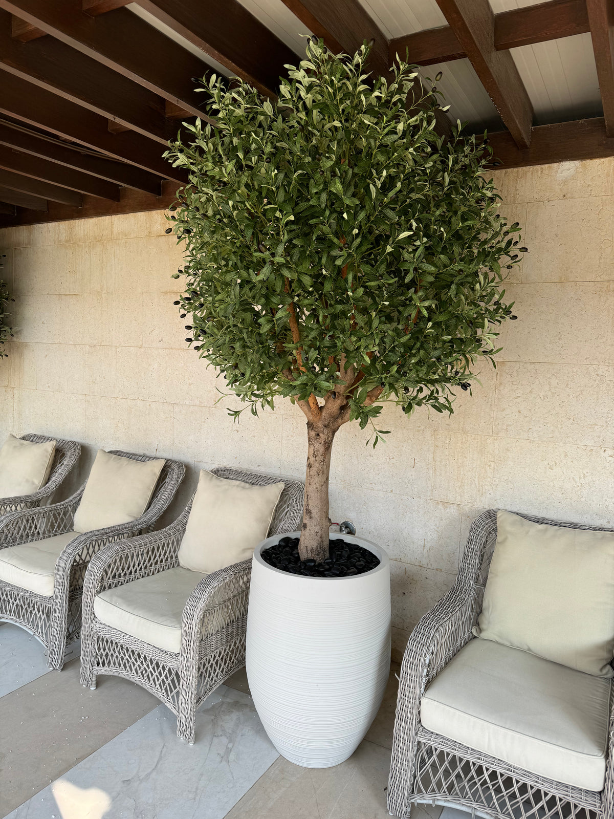 Artificial olive tree with dense green foliage in a white planter pot