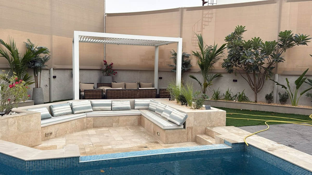 A white louvred pergola over sunken poolside seating, built by MyPlants at a villa in Dubai